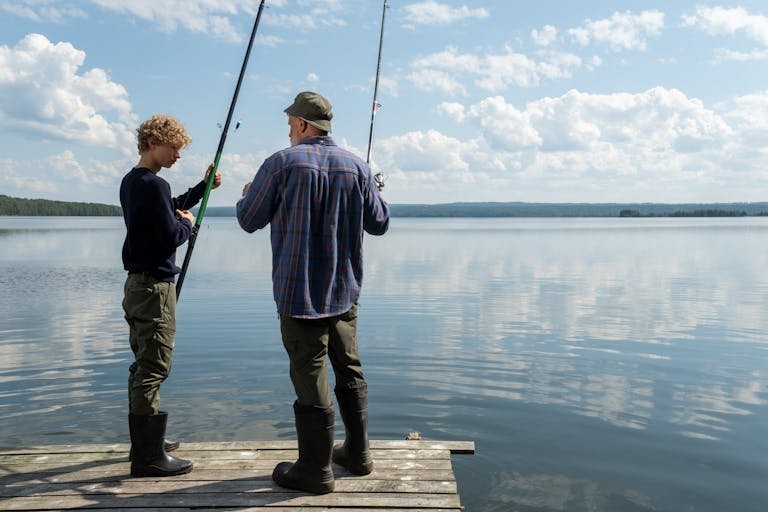A father and son fishing together on a peaceful lake dock, reflecting bonding moments.