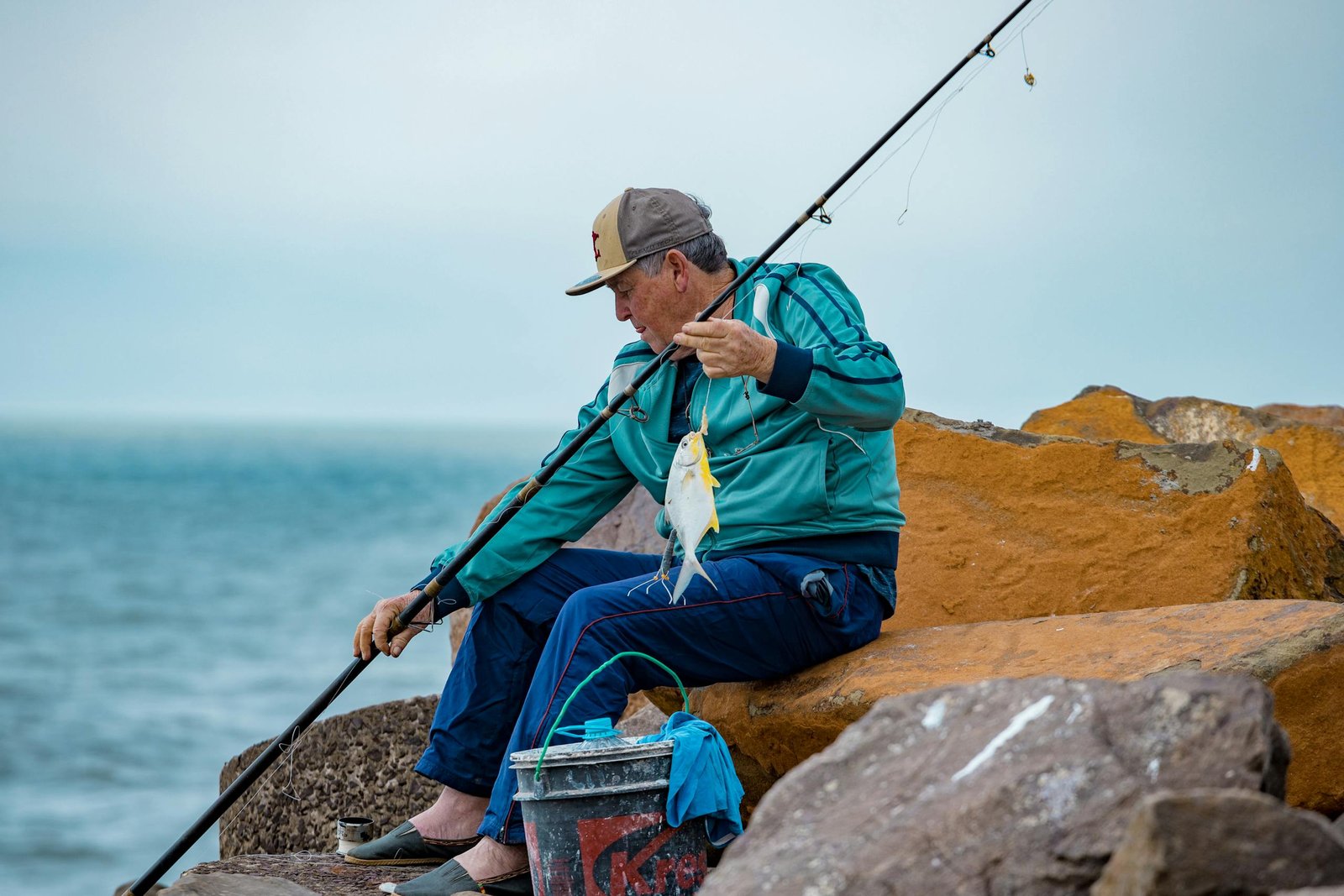 Fishing Techniques That Guarantee More Catches A senior man fishing on coastal rocks in Torres, Brasil, showcasing leisure and hobbies.