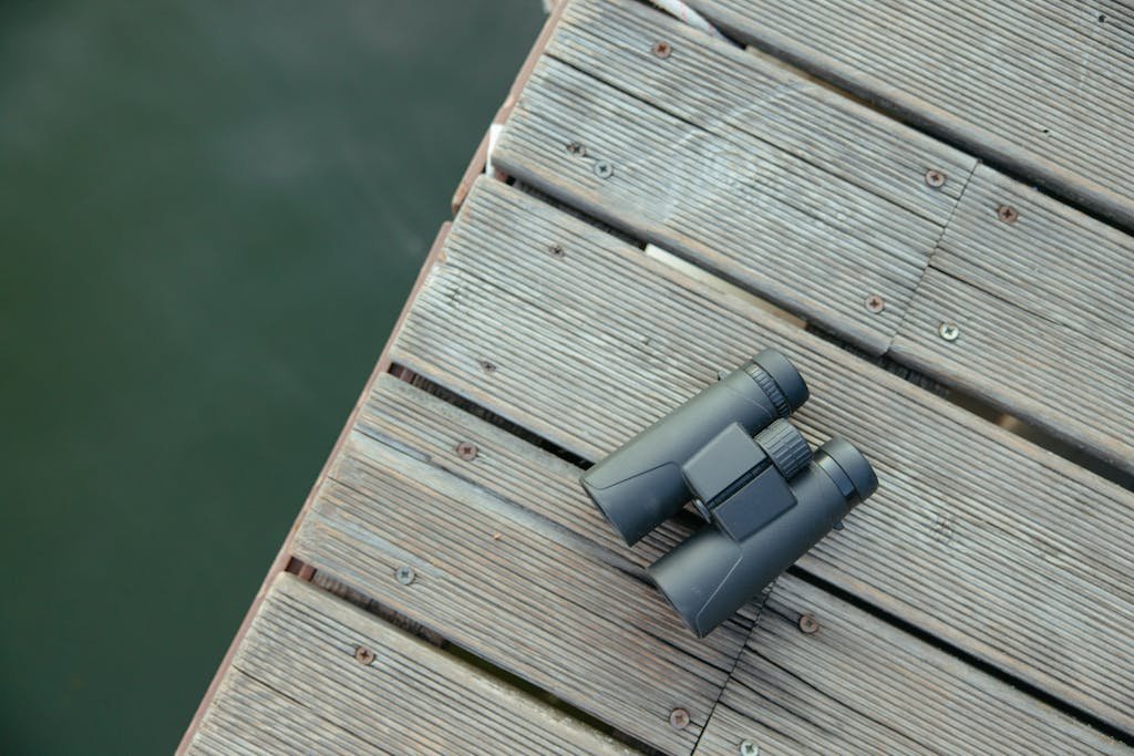 Best Fishing Spots in the US.
Black binoculars resting on a wooden dock with a view of water below.