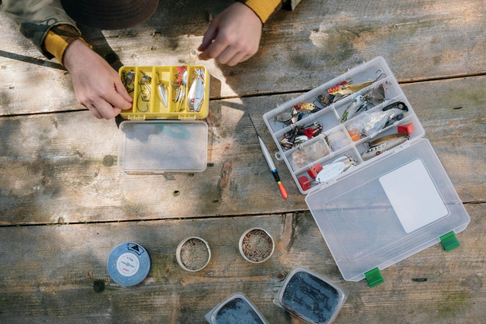 Fishing tools, boxes, and bait displayed on a rustic wooden surface for fishing enthusiasts.